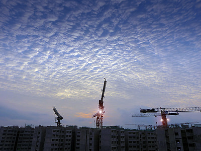three crane on top of concrete buildings thumbnail