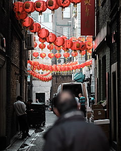people standing under red Chinese lanterns between high-rise building during daytime thumbnail