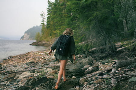 person wearing green dress shirt walking on rocky seashore thumbnail