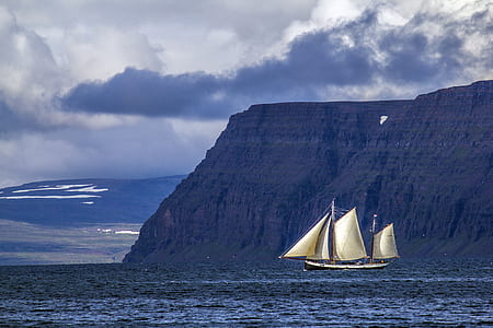 white boat sailing near mountain thumbnail