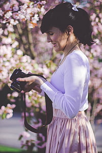 woman holding black camera surrounded by flowers thumbnail