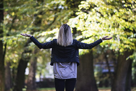woman raising two hands in front of trees thumbnail