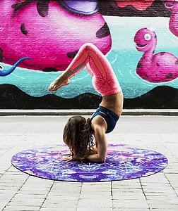 woman doing yoga position on round purple floral mat inside room thumbnail