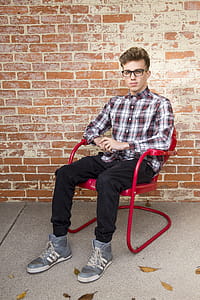 Man Wearing White And Red Long Sleeve Shirt Sitting On Red Steel Armchair thumbnail