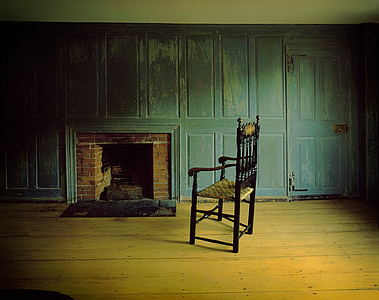 black wooden armchair near brown and black brick fireplace thumbnail