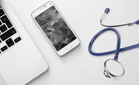 Photo of mobile phone, laptop and medical equipment - stethoscope and mobile medical concept. thumbnail