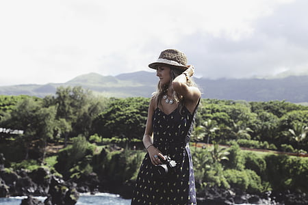 woman standing behind green tropical trees under cloudy sky during daytime thumbnail