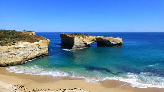 brown rock formation near large body of water and beach thumbnail