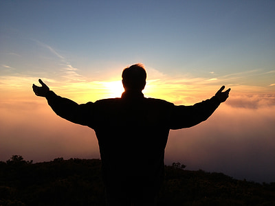 silhouette of man standing spreading his hand during golden hour thumbnail