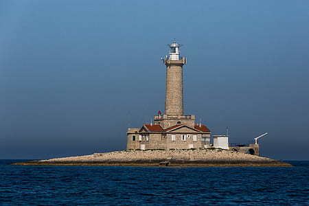 brown lighthouse under cloudy sky thumbnail