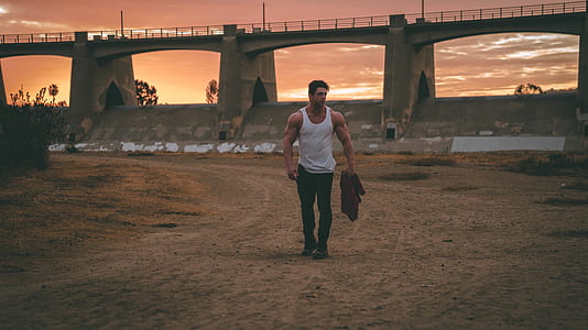 man walking near bridge holding black tops thumbnail
