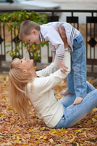 woman sitting on leaves holding boy thumbnail