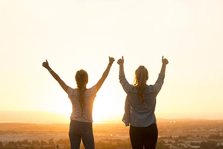 two women standing facing sunset thumbnail