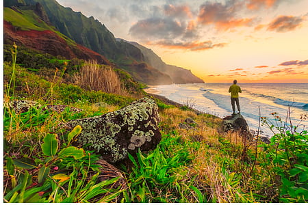 man standing on rock beside body of water during golden hour thumbnail