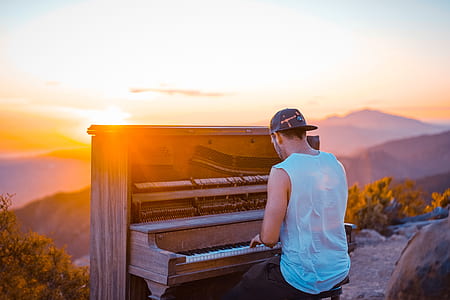 man wearing white tank top playing organ by the setting of the sun thumbnail