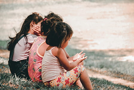 three girls sitting on beach during daytime thumbnail