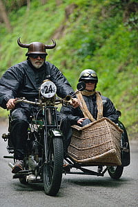 man riding motorcycle with viking helmet beside man sitting on sidecar thumbnail