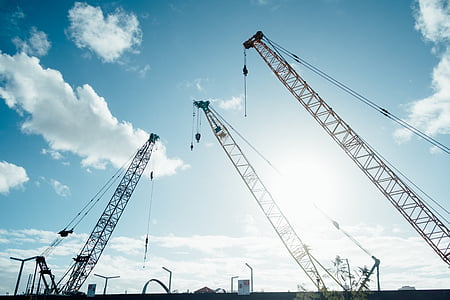 three crane machines under white clouds during daytime thumbnail