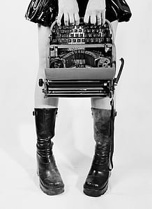 grayscale photograph of person holding type writer machine thumbnail