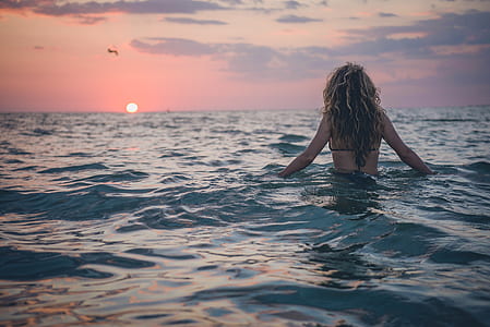 woman wearing bikini swimming on the beach during sunset thumbnail