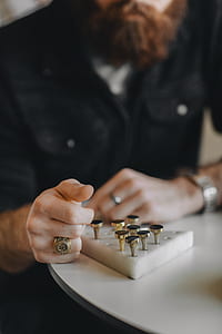 person's hand wearing gold-colored signet ring near handheld tool thumbnail