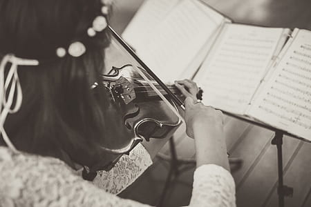 woman playing violin while looking at musical sheets grayscale photography thumbnail