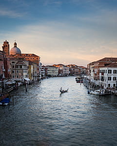Person Standing on Floating Boat Between Houses thumbnail