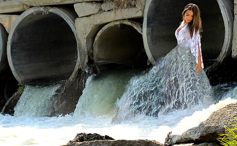 woman in white long-sleeved top beside open tunnel with flowing water thumbnail
