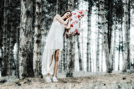 woman wearing white long dress while leaning on tree during daytime thumbnail