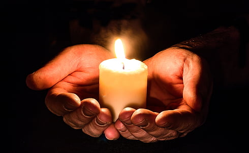 person holding pillar of candle with two hands thumbnail