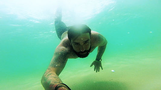 man swimming in body of water during daytime thumbnail