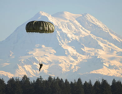 man using green parachute during daytime and mountain alps at distance thumbnail