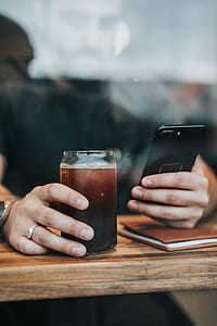 man holding both hands iPhone 7 Plus and a glass of beverage thumbnail