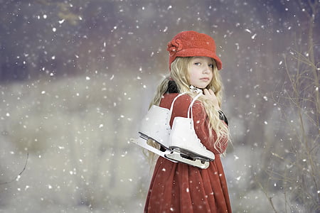 woman wearing red coat holding figure skate while raining snow thumbnail