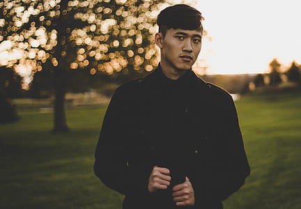 man in black jacket standing near tree thumbnail