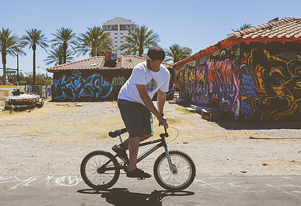 man in white crew-neck t-shirt riding black BMX bike during daytime thumbnail