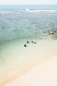 three person in body of water near sea shore thumbnail