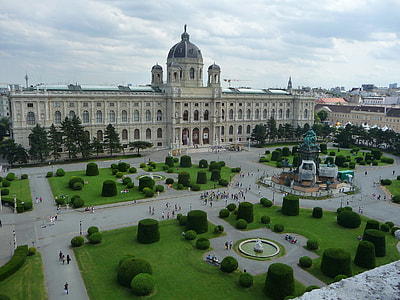 gray clouds over white dome palace with group of people walking outside the palace thumbnail