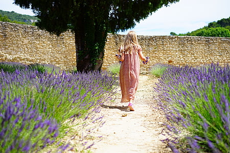 woman wearing pink dress standing near purple petaled flower during daytime thumbnail