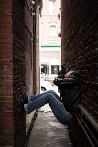 man curling in the middle of alley while taking photo during day thumbnail