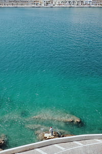 person standing on rock near body of water thumbnail