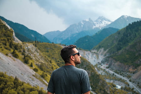man in gray t-shirt standing near view of mountains at daytime thumbnail
