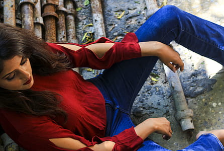 Woman Wearing Red Long-sleeved Top Sitting on Pile of Metal Pipes thumbnail