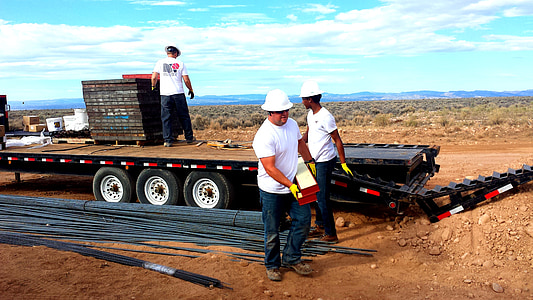 man carrying bar beside flat-bed truck thumbnail