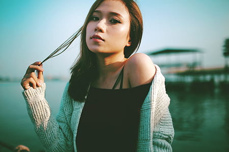 woman holding the strands of her hair at the dock during day thumbnail
