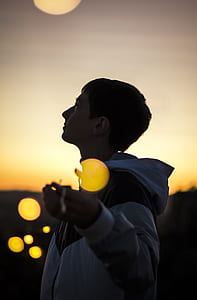 boy with white and black zip-up hooded windbreaker jacket during golden hour thumbnail