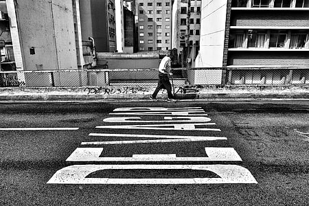 grayscale photography of man walking beside road thumbnail