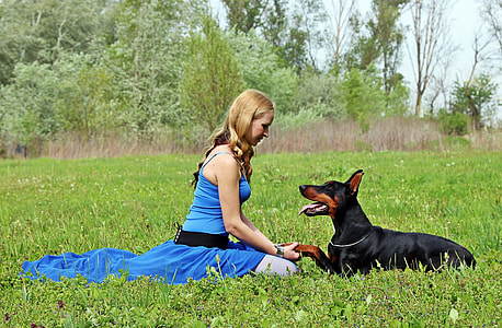 woman sitting in front of black Dorbermann thumbnail