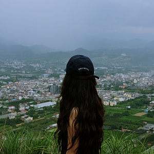 person wearing black cap looking at city view under cloudy skies thumbnail