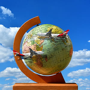 two white airplanes hanging on globe under white clouds and blue sky thumbnail